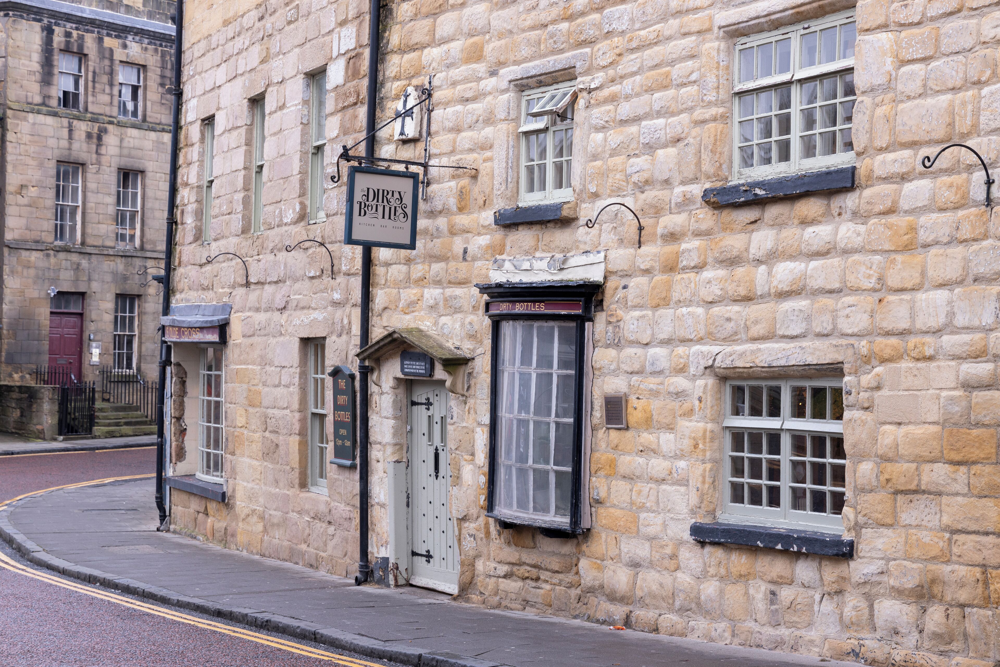 Un bâtiment en pierre avec une enseigne indiquant « Bouteilles vides » et une porte fermée.