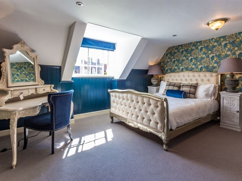 A bedroom with a bed, a dresser, a chair, and a window.