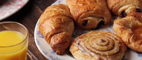 A plate of croissants and a glass of orange juice on a wooden table.