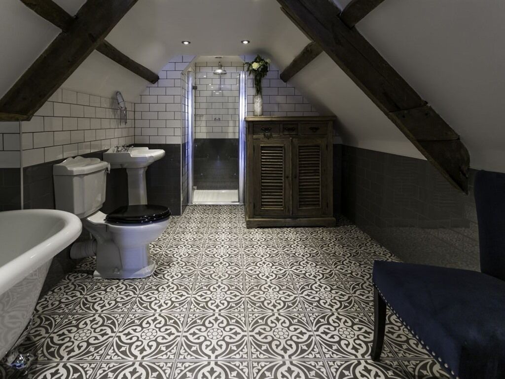 A bathroom with a white and black patterned floor, a white sink, a toilet, and a wooden cabinet.
