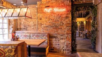 A rustic interior with exposed brick walls, wooden furniture, and a neon sign.