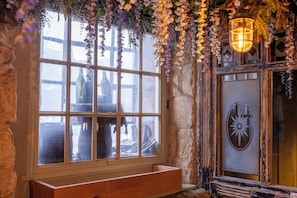 A rustic room with a large window, a wooden bench, and a lantern. - Dirty Bottles (Alnwick)