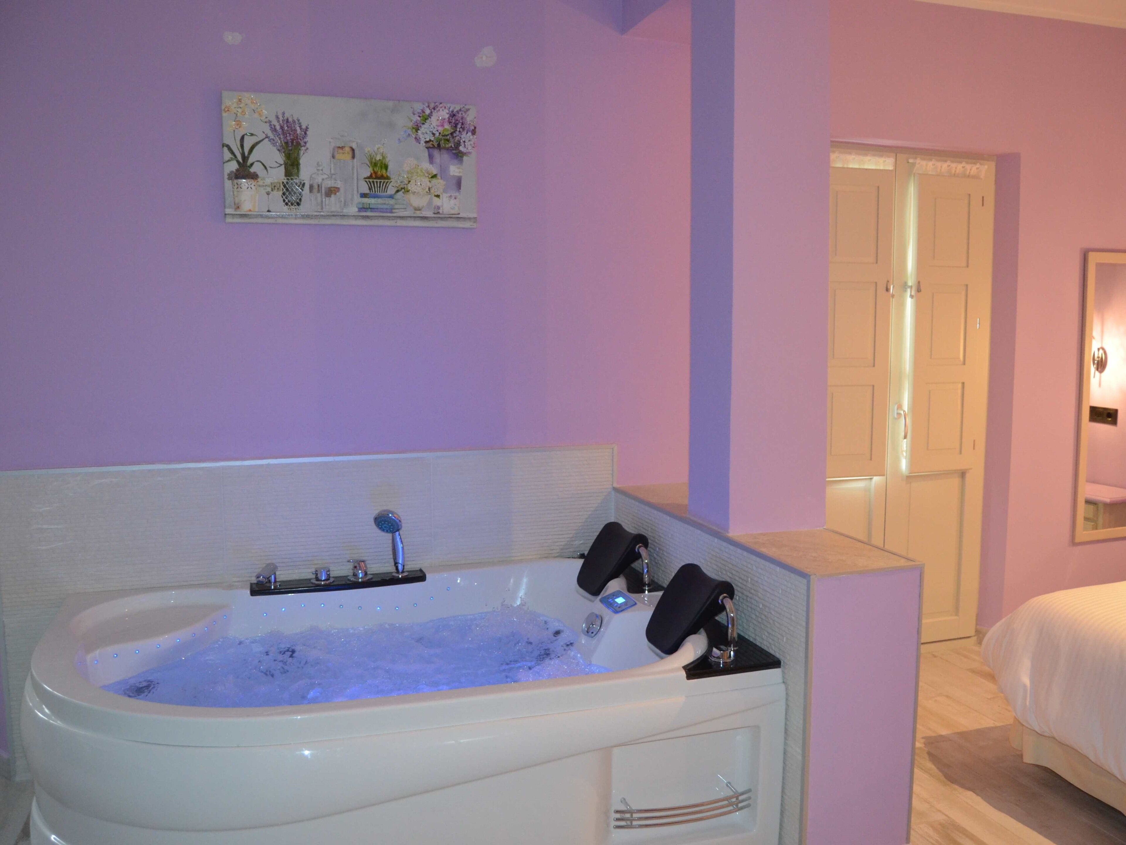 A modern bathroom with a large freestanding bathtub, a shower, and a door leading to another room.