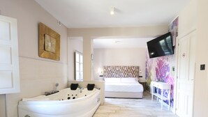 Un baño moderno con una bañera independiente, un espejo grande y un televisor instalado en la pared.
