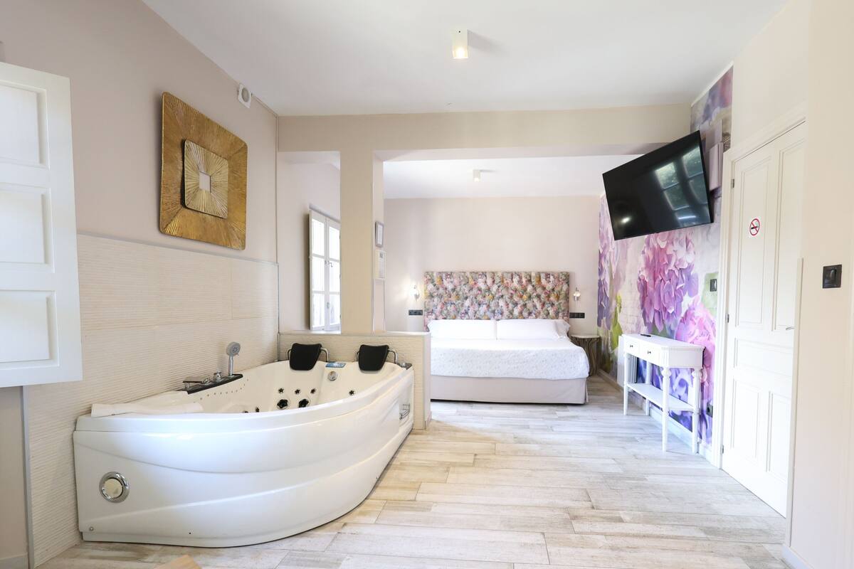 Un baño moderno con una bañera independiente, un espejo grande y un televisor instalado en la pared.
