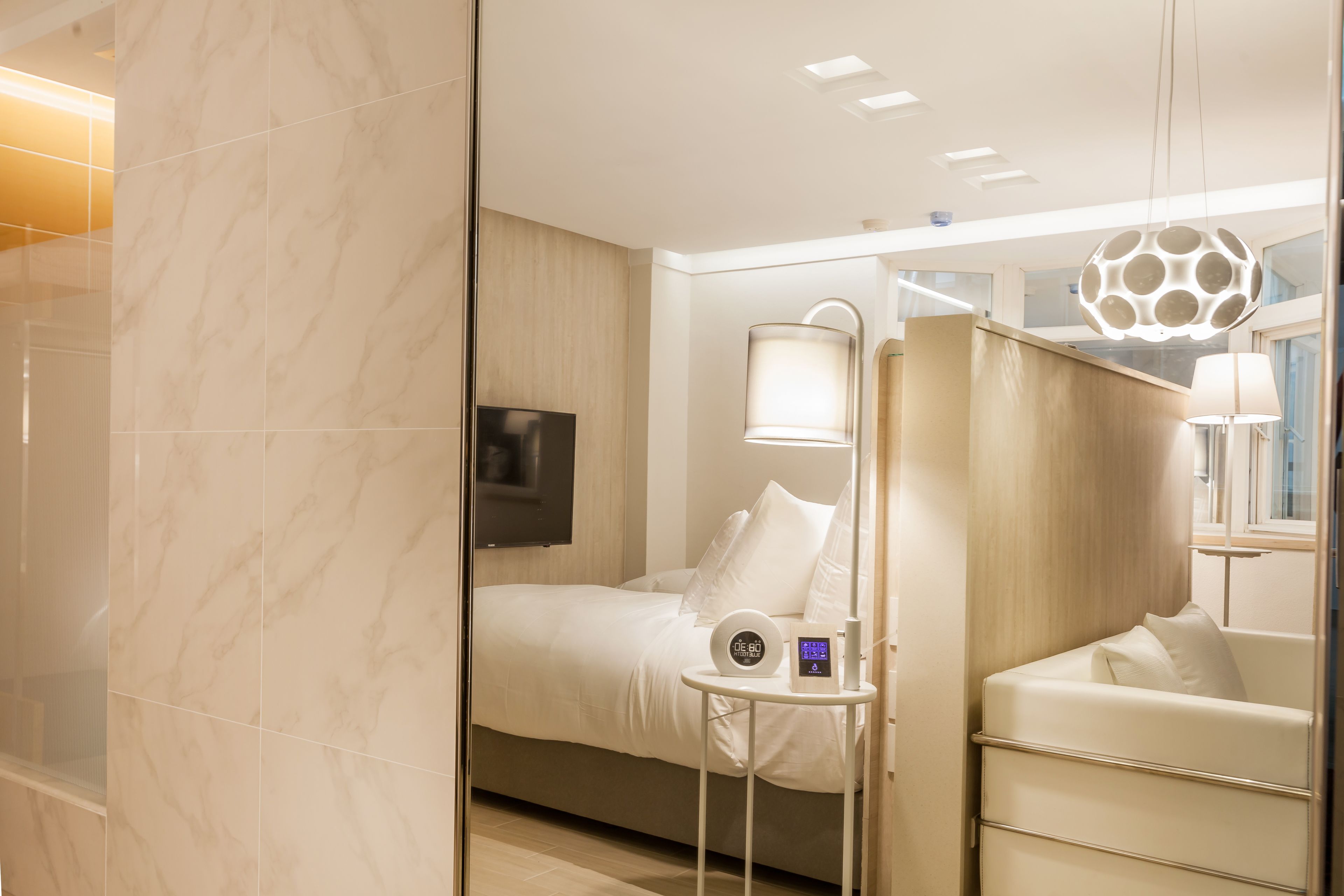Una habitación de hotel moderna con una cama, mesita de noche, lámpara y televisión.