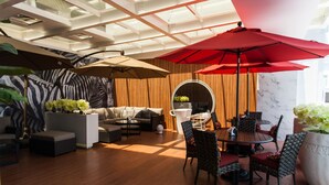 A modern lounge area with a wooden floor, a round table with chairs, a sofa, and a large red umbrella. - Six Star Motel - Taoyuan (Taoyuan City)