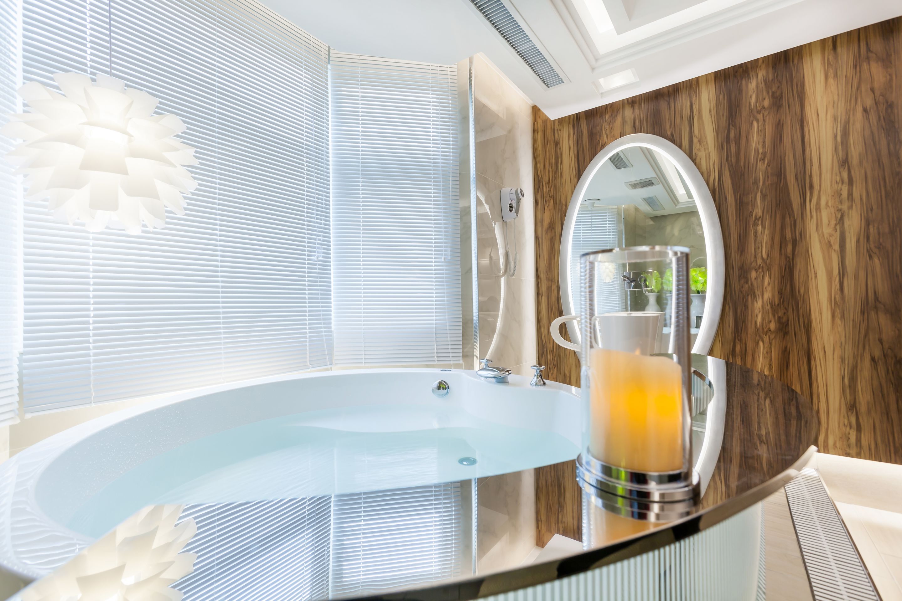 Een moderne badkamer met een glazen badkuip, een houten accentmuur en een grote spiegel.