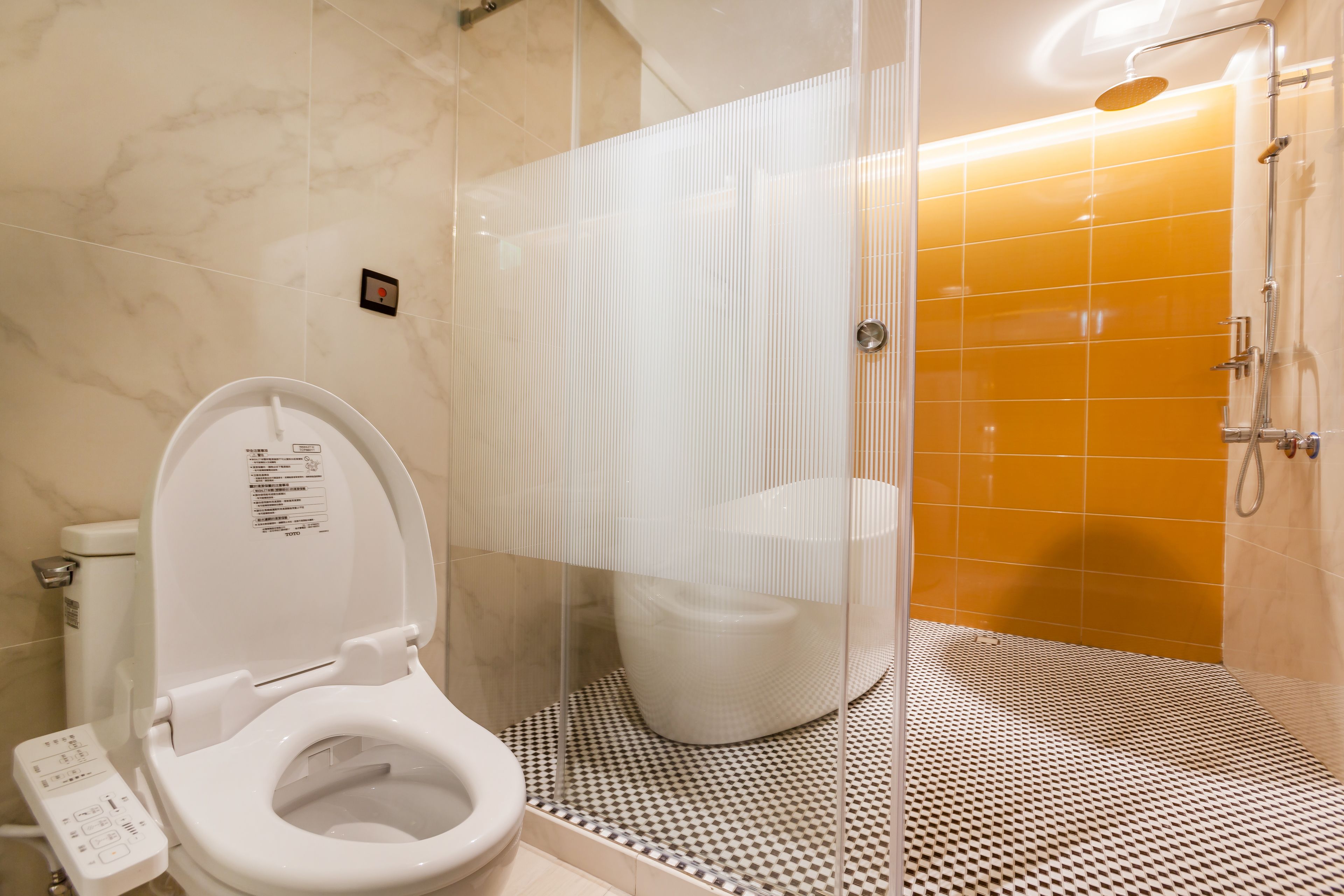 Un baño moderno con inodoro, cabina de ducha y suelo estampado.