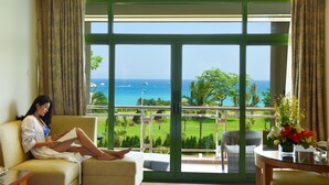 A room with a large window overlooking a golf course and the ocean.