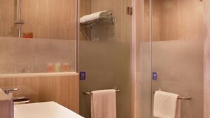 A modern bathroom with a glass-enclosed shower, a white sink, and a towel rack.