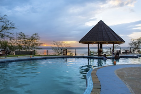 Una piscina al aire libre, sombrillas, sillones reclinables de piscina