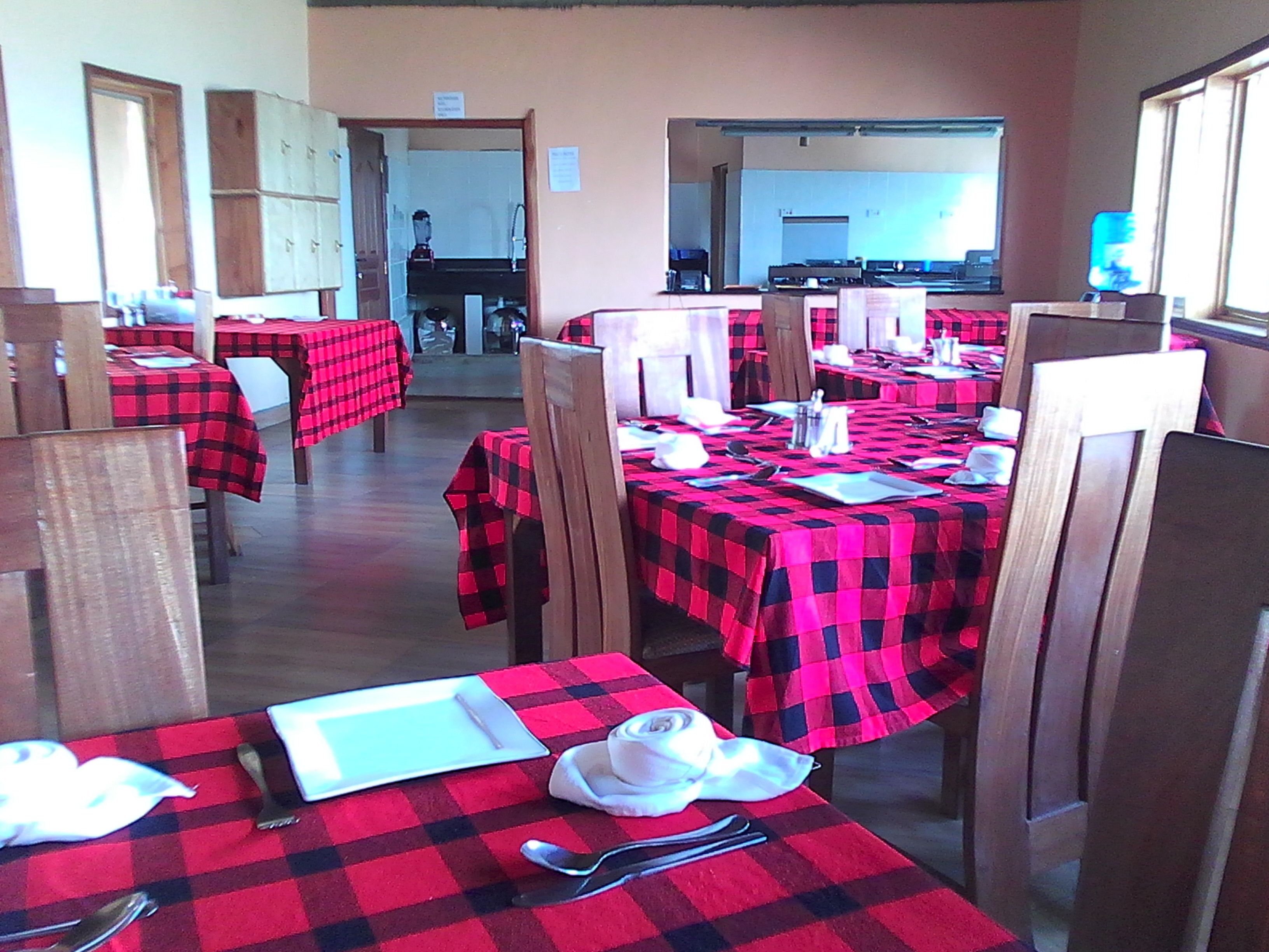 Ein Restaurant mit Tischen, die mit rot-schwarz karierten Tischdecken bedeckt sind, Holzhöhlen und einer Küche im Hintergrund.