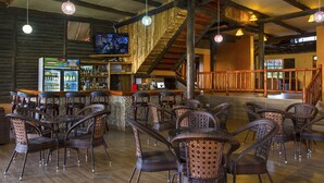 A restaurant with wicker furniture, a bar area, and a television screen. - Sirville Lake Elementaita Lodge (Gilgil)