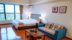 A hotel room with a bed, a blue sofa, a wooden coffee table, and a window with curtains. - Live Inn Luogang Wanda Square Branch (Guangzhou)