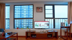 A living room with a TV, wooden furniture, and large windows with blinds. - Live Inn Luogang Wanda Square Branch (Guangzhou)