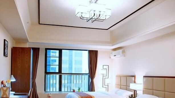 A hotel room with a large bed, a desk, a chair, a small table, and a window with curtains. - Live Inn Luogang Wanda Square Branch (Guangzhou)