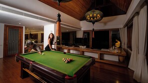 A pool table with balls, a person playing, and a billiard cue. - Villa Riva (Koh Samui)