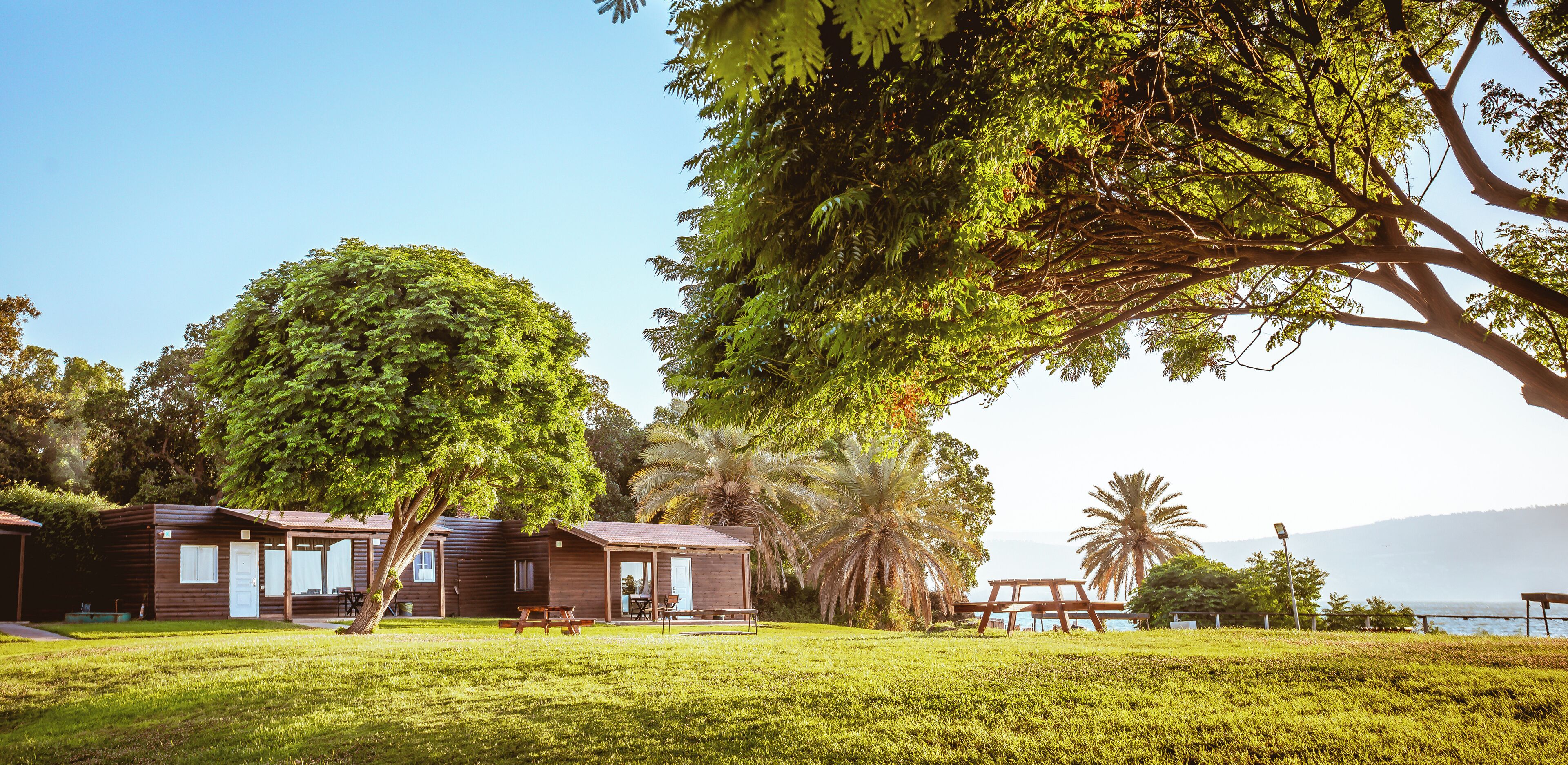 A row of wooden cabins with picnic tables and a view of the ocean.