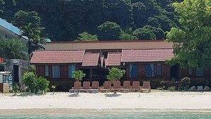 Un edificio frente a la playa con techo de tejas, varias ventanas y una playa arenosa.