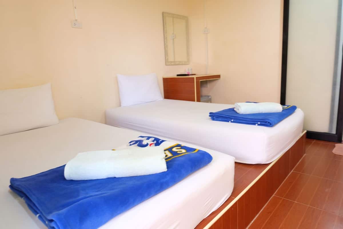 Habitación de hotel con dos camas, una mesita de noche pequeña, un espejo y vistas al exterior.