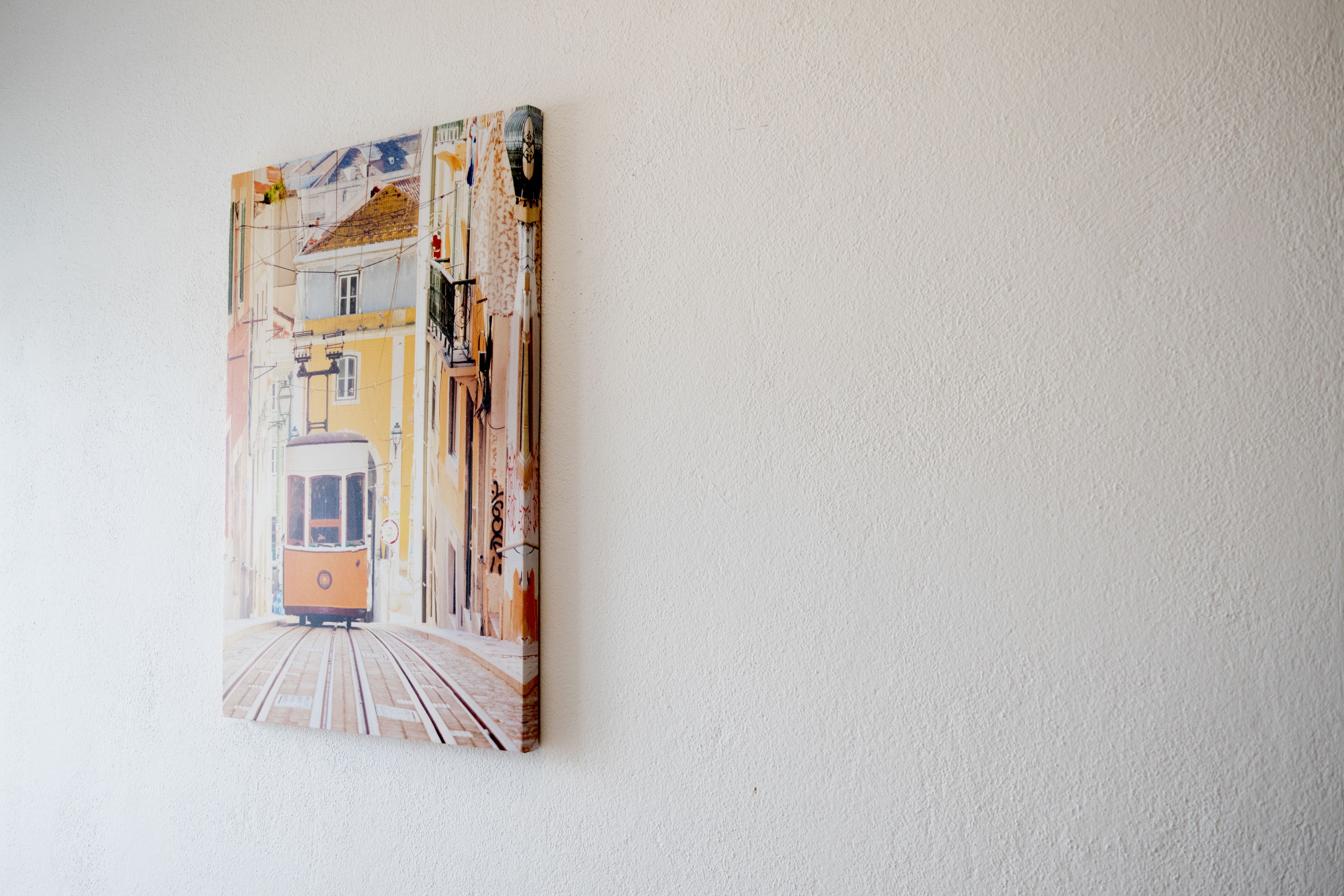 A painting of a tram on a track, mounted on a textured wall.