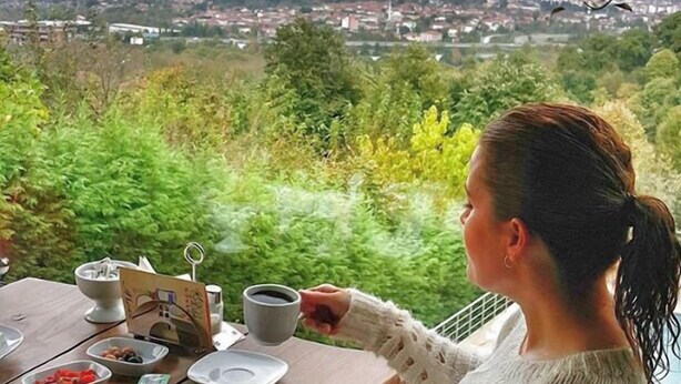 A person seated at a table with a meal, overlooking a cityscape and greenery. - Dilek Konağı (Sapanca)