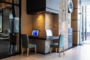 Een moderne receptiebalie met twee stoelen, een computer en een digitaal scherm.