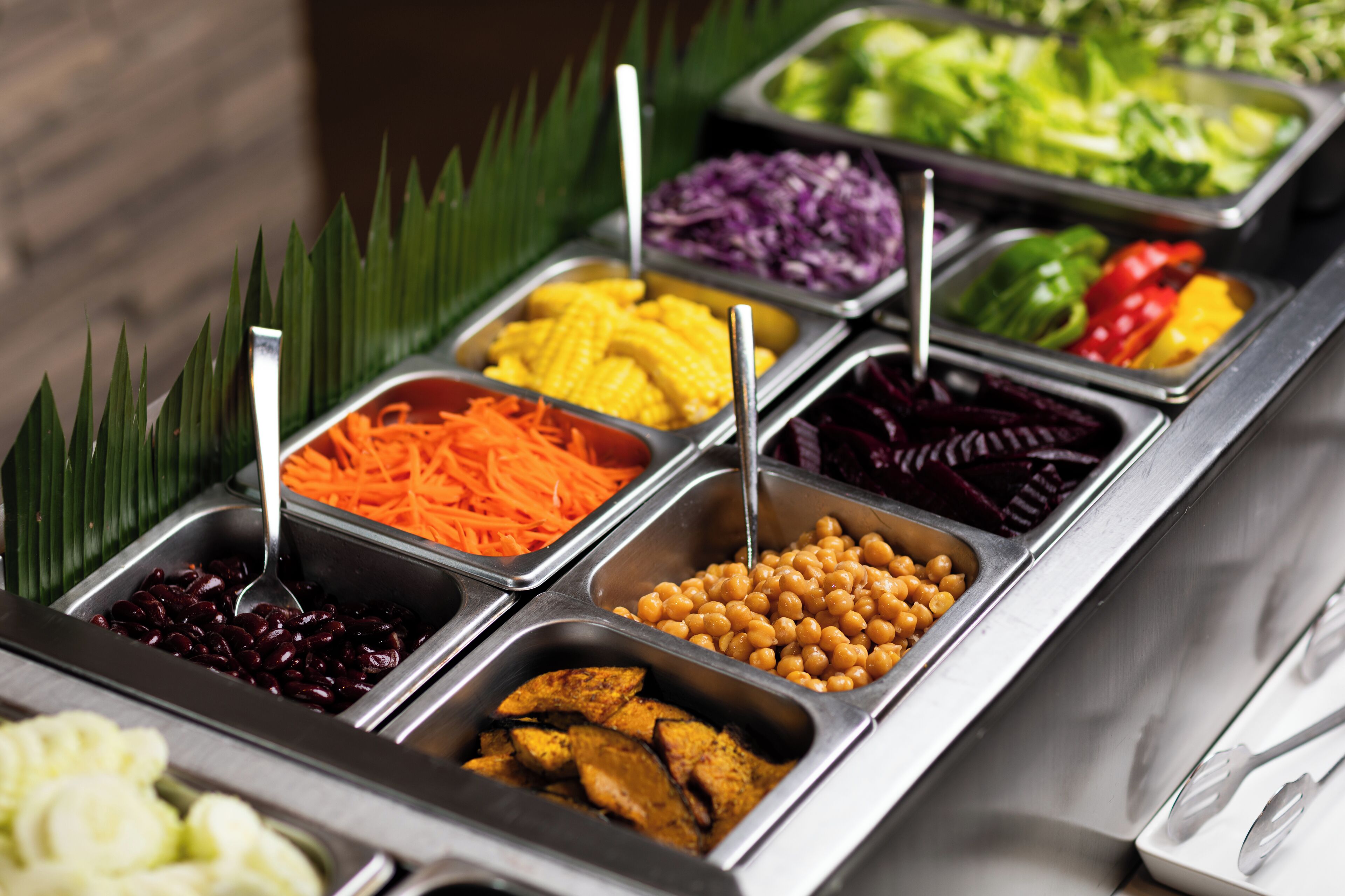 Un bufé con diversas opciones de comida, incluyendo verduras, legumbres y carnes.
