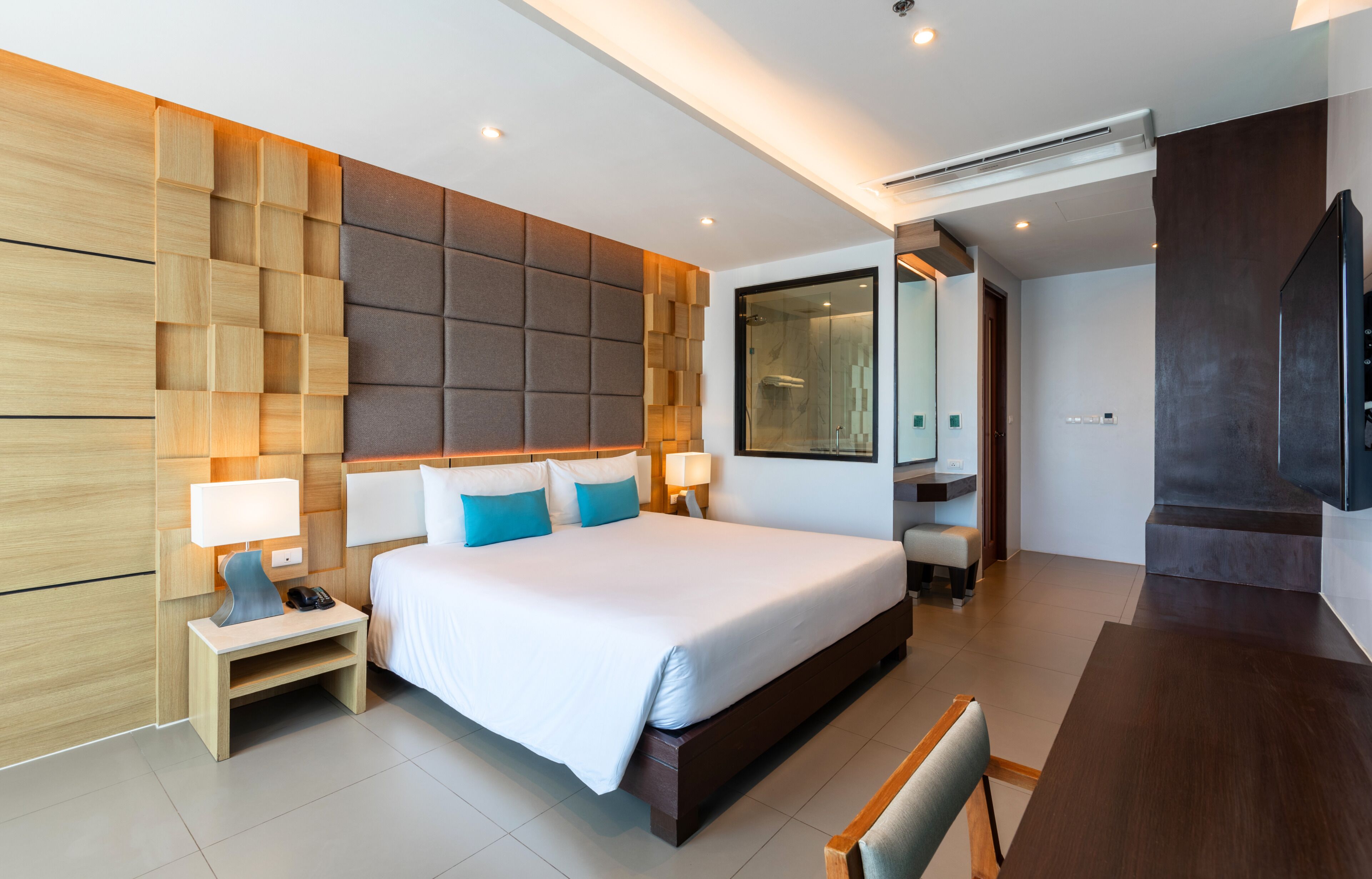 A modern hotel room with a large bed, bedside tables, a desk, and a TV.