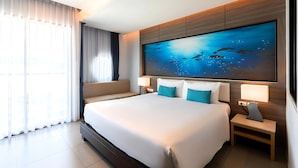 Una camera d'albergo moderna con un ampio letto, una TV a parete e vista sull'oceano dalla finestra.
