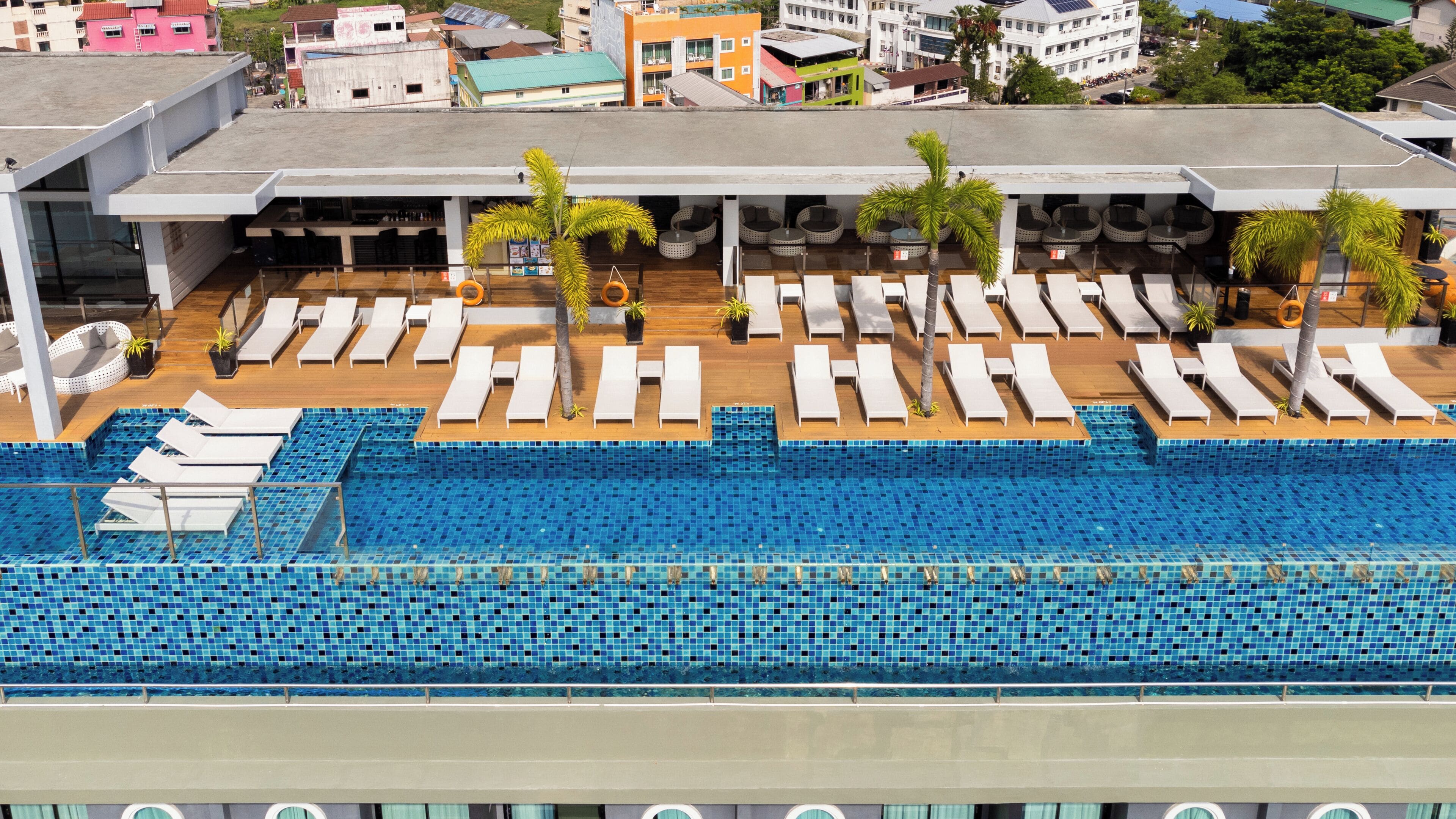 A rooftop pool area with multiple lounge chairs and a swimming pool.