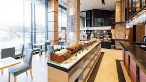 Una hall d'albergo moderna con un'area buffet, posti a sedere e un angolo caffè.