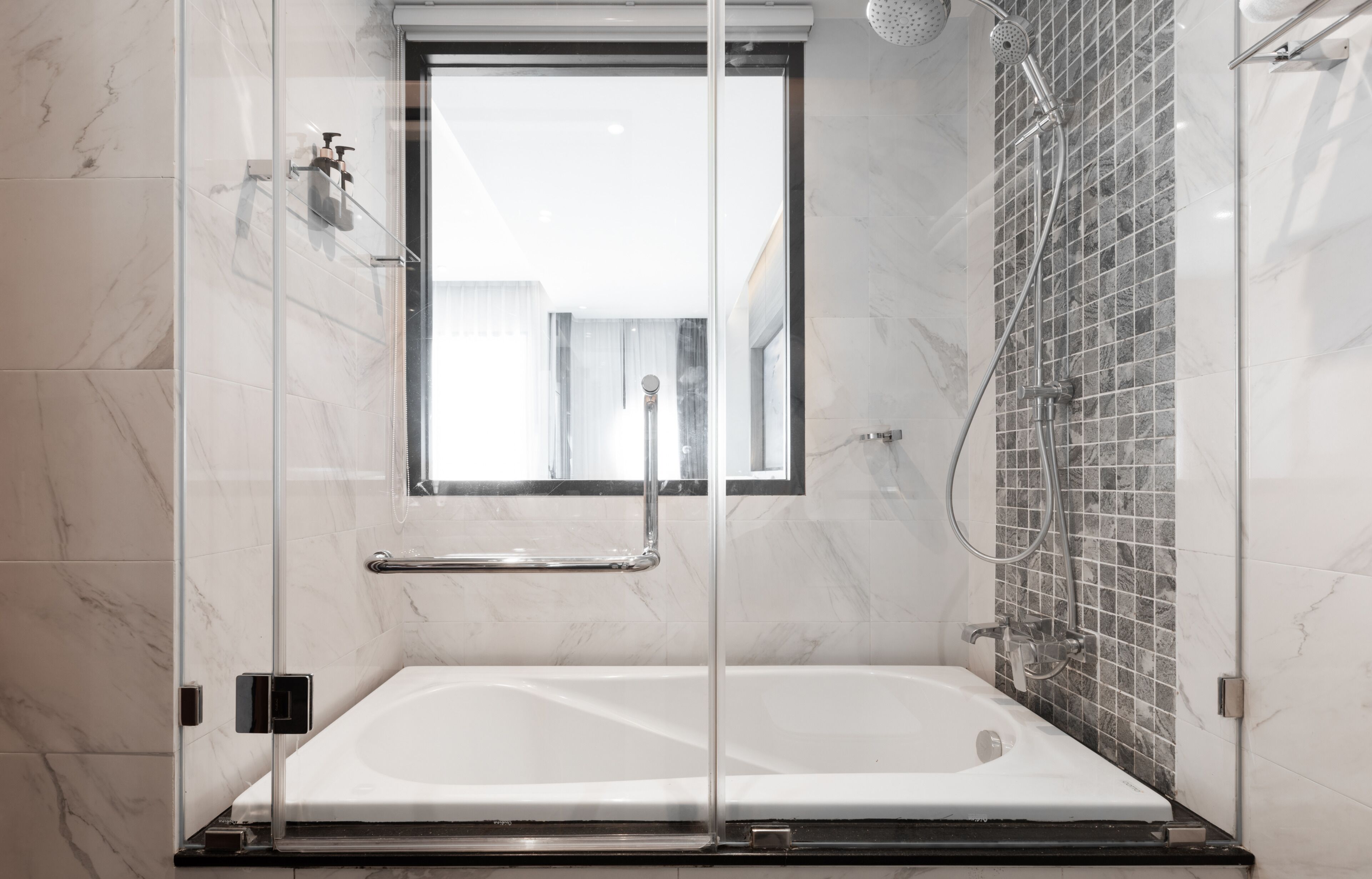 Une salle de bain moderne avec une douche à parois de verre, une grande baignoire et un mur carrelé agrémenté d’une fenêtre.
