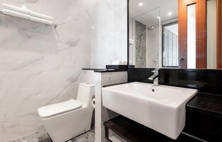 Un baño moderno con inodoro y lavamanos blancos, y un espejo grande.