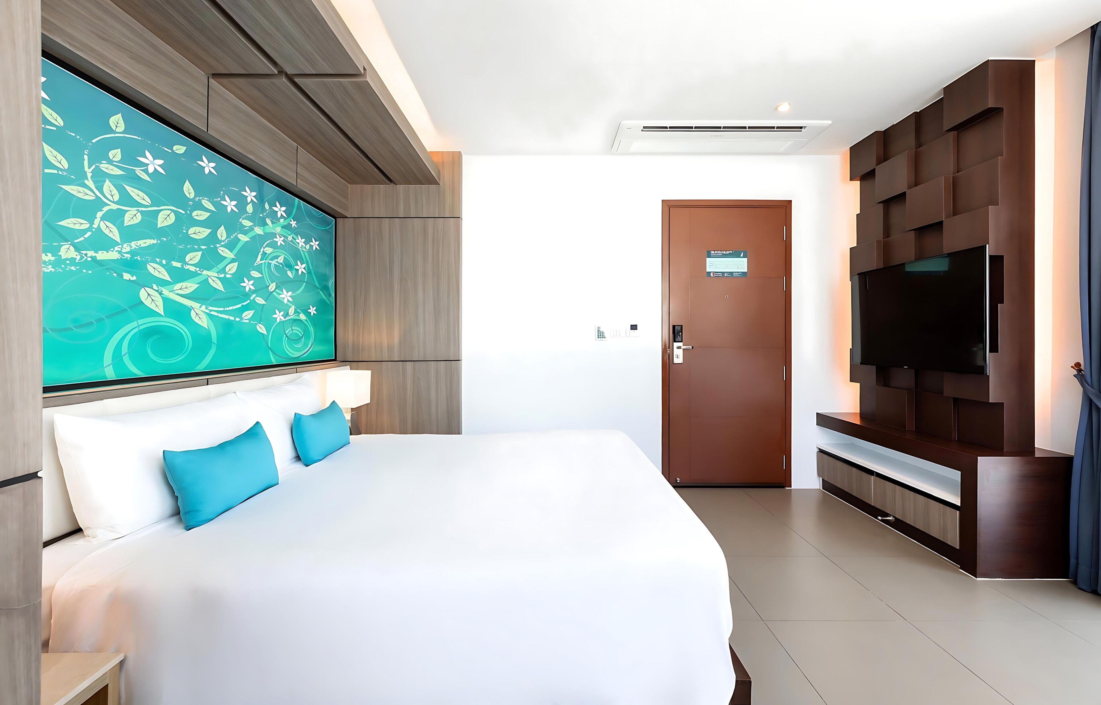 A modern hotel room with a large bed, a wall-mounted TV, and a large artwork.