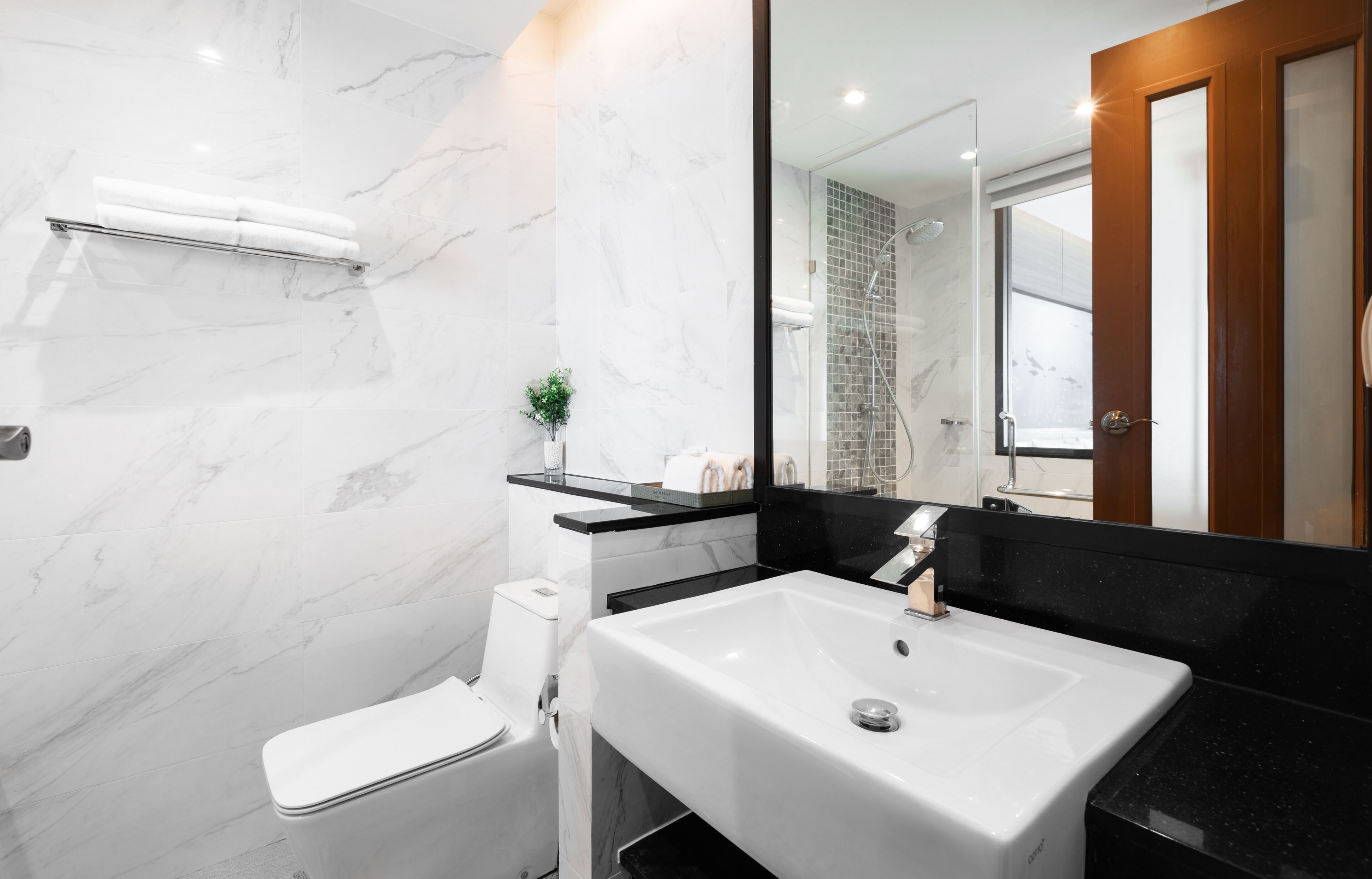 A modern bathroom with a white toilet, a white sink, and a glass shower enclosure.