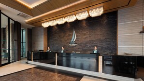 Una reception con un logo, un lampadario e un arredamento moderno.