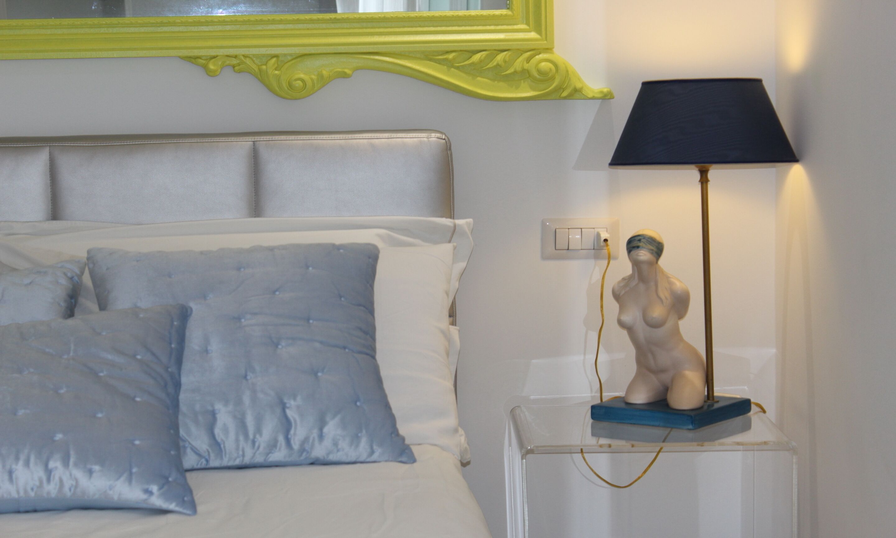 Un lit avec une tête de lit, une lampe de chevet et une petite statue posée sur une table de chevet.