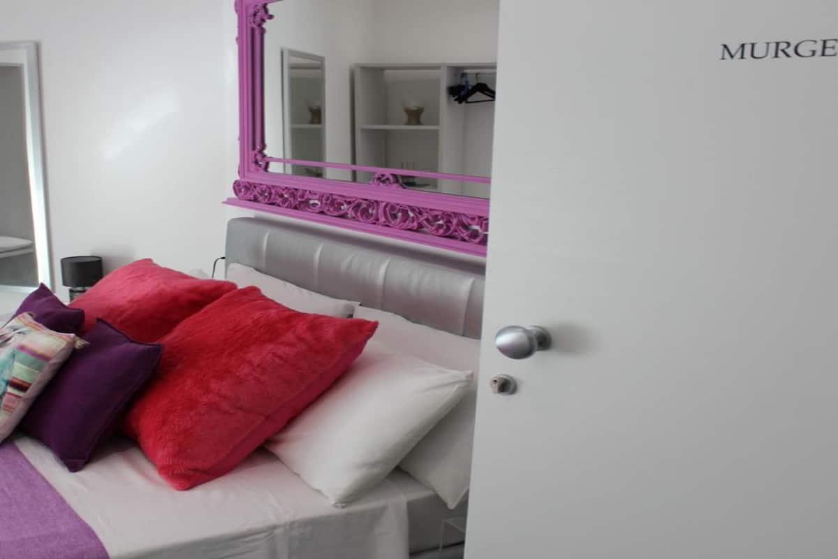 Un dormitorio con cama, almohadas, un espejo y un armario.