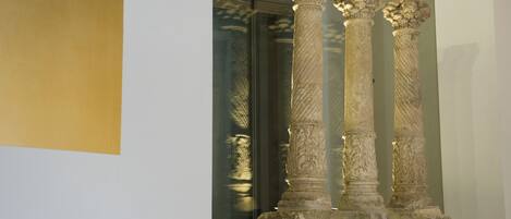 Three ancient columns with intricate carvings, positioned in a well-lit indoor space.