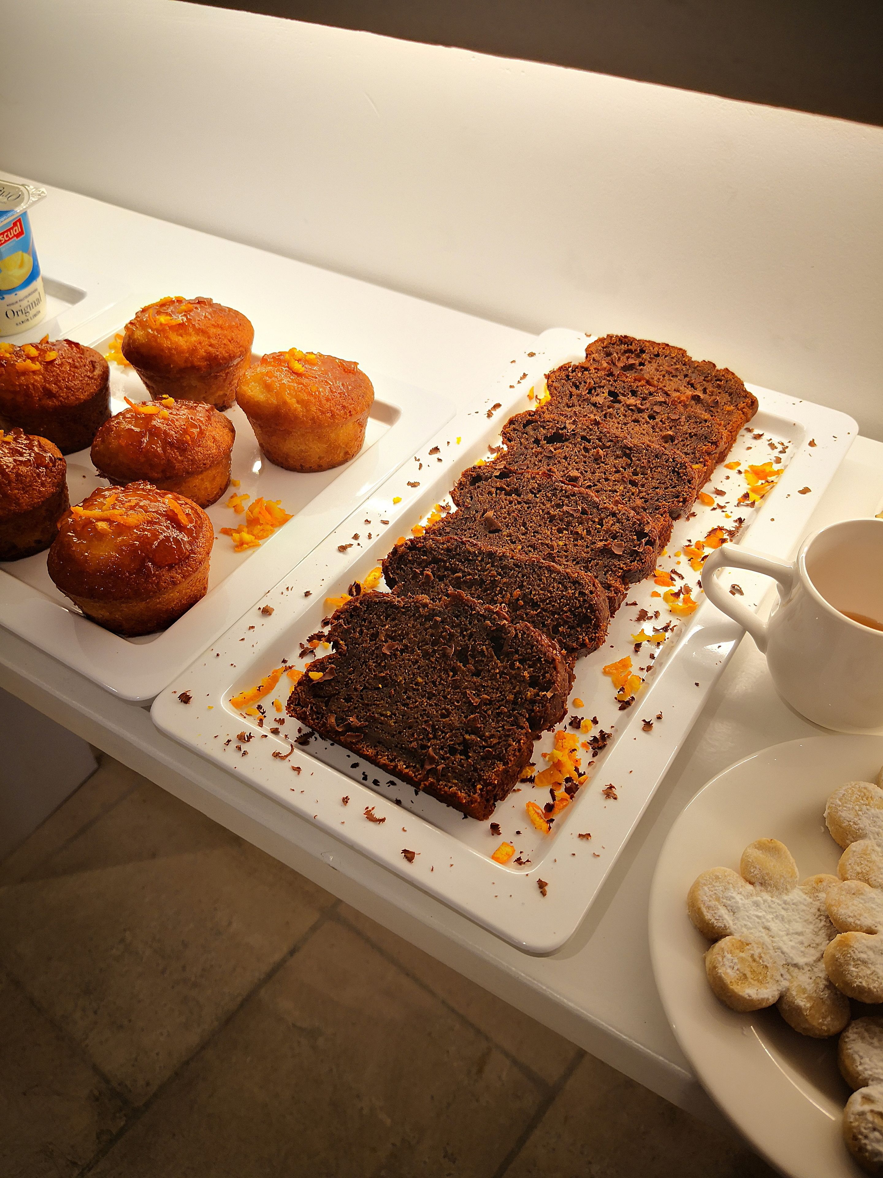 A tray with brownies and muffins, a mug, and some cookies on a table.