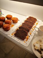 A tray with brownies and muffins, a mug, and some cookies on a table.