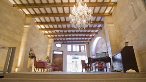 A grand lobby with a chandelier, marble columns, and a piano. - Sindic Hotel - Adults Only (Mahón)