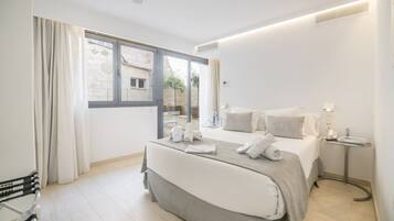 A modern hotel room with a large bed, a bedside table, and a window with curtains.