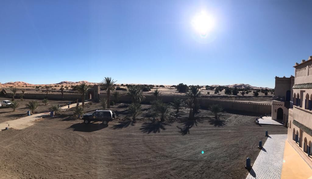 A desert landscape with a building featuring arched windows and a tiled entrance.
