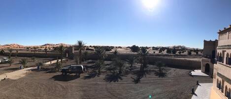 A desert landscape with a building featuring arched windows and a tiled entrance.