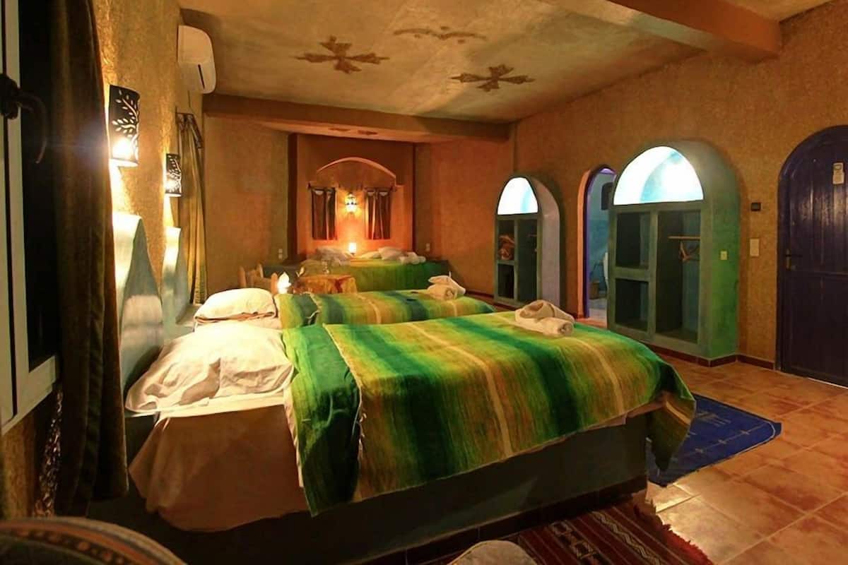 Habitación de hotel con dos camas, un espejo grande y una mesita.