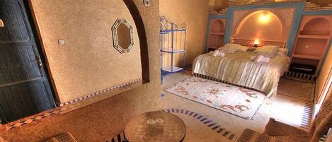 A room with a bed, a small table, and a decorative mirror.