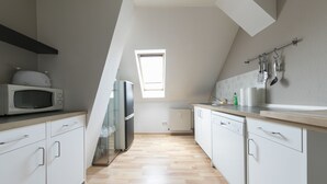 Eine moderne Küche mit weißen Schränken, einer Mikrowelle, einem Kühlschrank und einem Oberlicht.